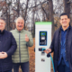 Drei personen stehen im Wald vor einer Ladesäule